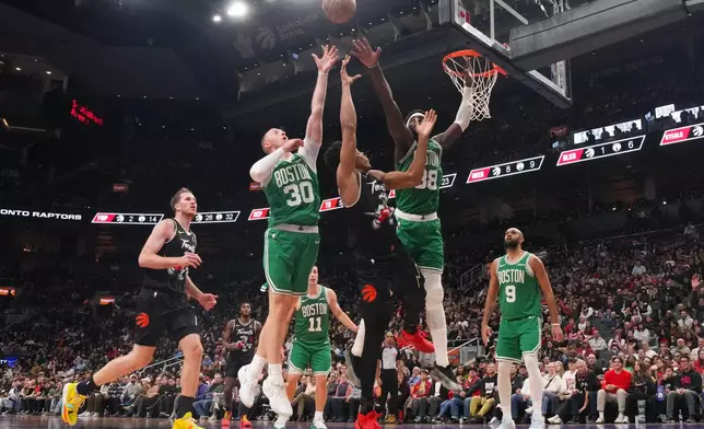 Toronto Raptors forward Scottie Barnes, center, shoots over Boston Celtics Sam Hauser (30) and Neemias Queta (88) during first-half NBA basketball game action in Toronto, Sunday Dec. 7, 2025. (Chris Young/The Canadian Press via AP)
