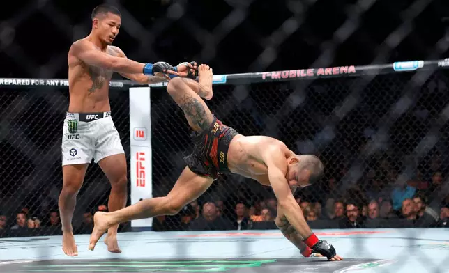 UFC flyweight champion Alexandre Pantoja, right, is injured as he falls to the canvas away from Joshua Van during UFC 323 Saturday, Dec. 6, 2025, in Las Vegas. (Steve Marcus/Las Vegas Sun via AP)