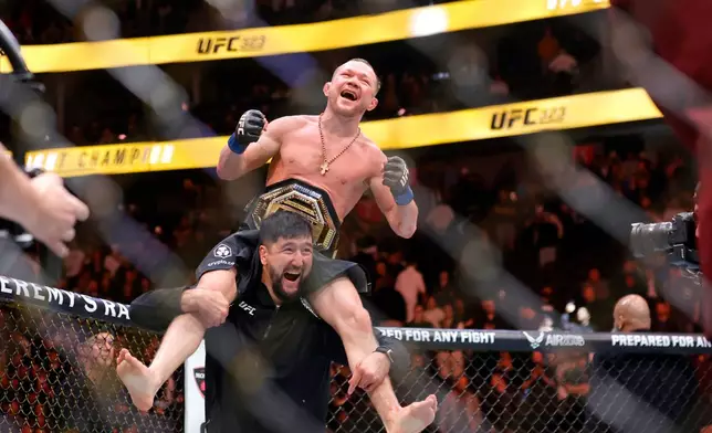 Petr Yan celebrates with a member of his team after defeating UFC bantamweight champion Merab Dvalishvili during UFC 323 Saturday, Dec. 6, 2025, in Las Vegas. (Steve Marcus/Las Vegas Sun via AP)