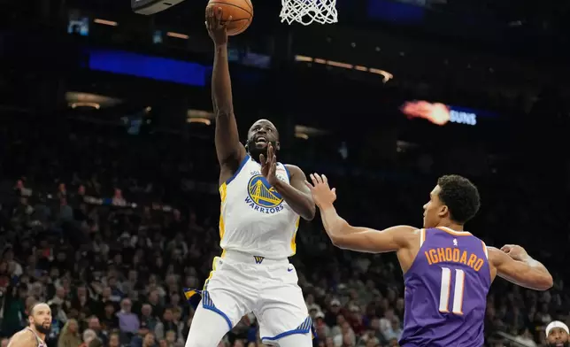 Golden State Warriors forward Draymond Green, left, drives past Phoenix Suns forward Oso Ighodaro (11) to score during the first half of an NBA basketball game Thursday, Dec. 18, 2025, in Phoenix. (AP Photo/Ross D. Franklin)