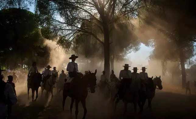 Pilgrims ride through dusty terrain, on their way to the shrine of El Rocio during the annual pilgrimage, near Aznalcázar, Spain, June 6, 2025. (AP Photo/Emilio Morenatti, File)