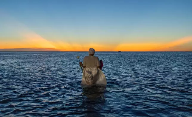 A woman wades into the waters of Ramirez Beach as part of a ritual honoring the African sea goddess Yemanja, in Montevideo, Uruguay, Feb. 2, 2025. (AP Photo/Matilde Campodonico, File)