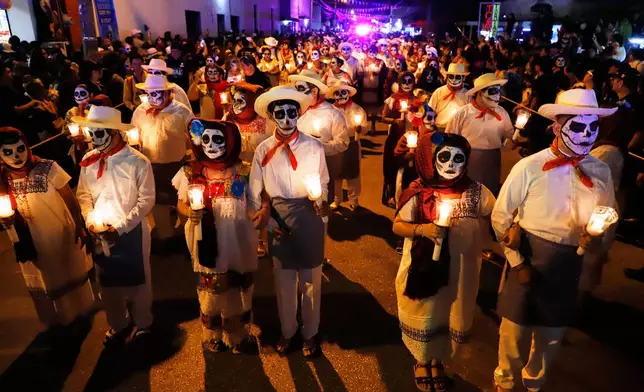 People with skull make up on their faces, march during the Paseo de las Animas parade as part of the Day of the Dead celebrations, in Merida, Mexico, Oct. 31, 2025. (AP Photo/Martin Zetina, File)