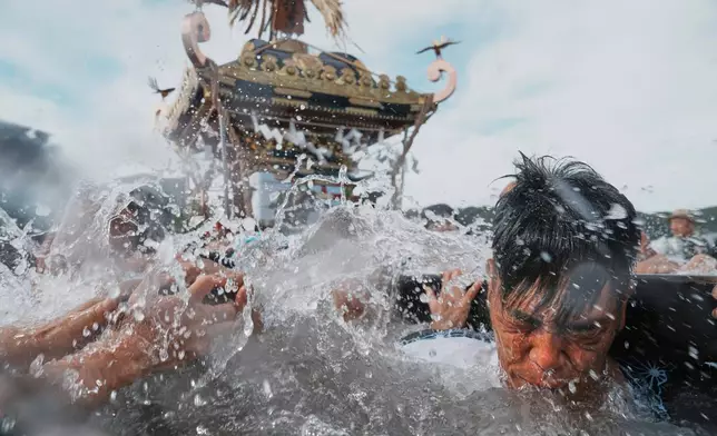 Participants carry a portable shrine, or mikoshi, into the sea during a purification rite at the annual Kurihama Sumiyoshi Shrine Festival at Kurihama, Yokosuka city, south of Tokyo, July 27, 2025. (AP Photo/Eugene Hoshiko, File)