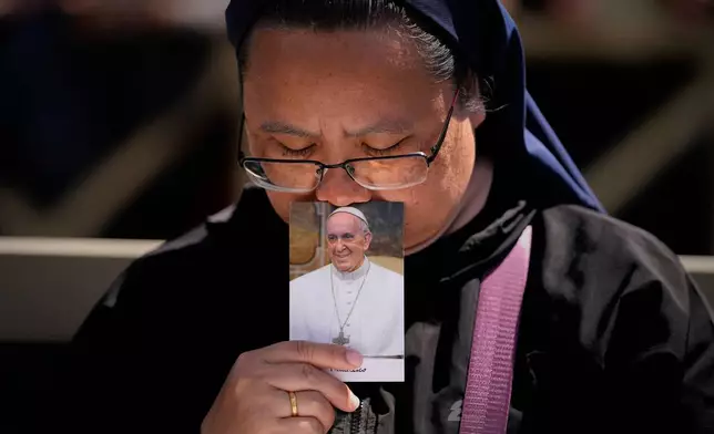 A nun holds a photo of Pope Francis while attending his funeral, in St. Peter's Square at the Vatican, April 26, 2025. (AP Photo/Andreea Alexandru, File)