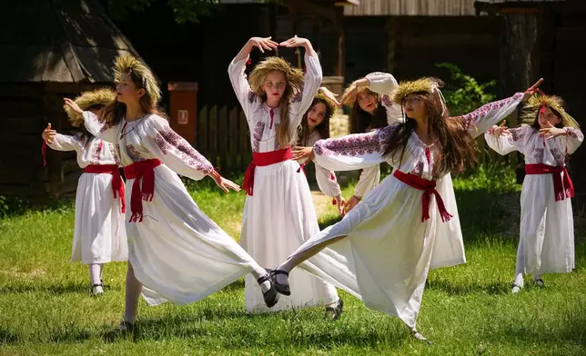 Girls, wearing crowns made of flowers, dance during the 'Sanziene' midsummer festival at the Dimitrie Gusti Village Museum, in Bucharest, Romania, June 24, 2025. (AP Photo/Andreea Alexandru, File)