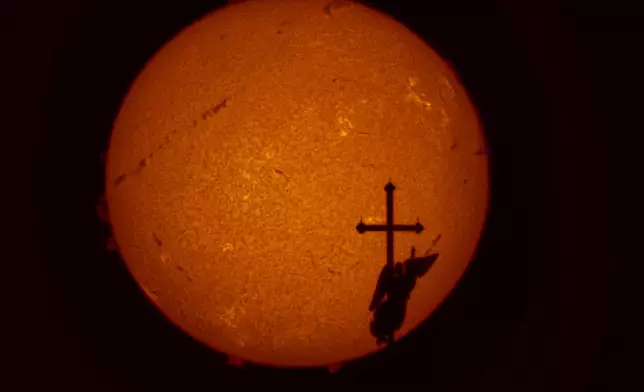 A weather vane in the form of an angel on top of the spire of the Saints Peter and Paul Cathedral is silhouetted against the sun showing solar activity zones, photographed by a solar telescope, in St. Petersburg, Russia, on Aug. 21, 2025. (AP Photo/Dmitri Lovetsky, File)