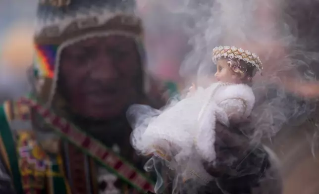An Aymara Indigenous spiritual guide blesses a statue of baby Jesus with incense after an Epiphany Mass at a Catholic church in La Paz, Bolivia, Jan. 6, 2025. (AP Photo/Juan Karita, File)