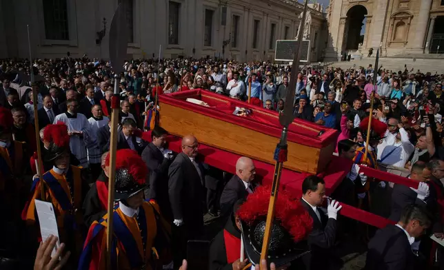 The body of Pope Francis is carried into St. Peter's Basilica to lie in state for three days, at the Vatican, April 23, 2025, (AP Photo/Emilio Morenatti, File)
