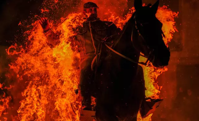A man rides a horse through a bonfire as part of a ritual in honor of Saint Anthony the Abbot, the patron saint of domestic animals, in San Bartolome de Pinares, Spain, Jan. 16, 2025. (AP Photo/Manu Fernandez, File)