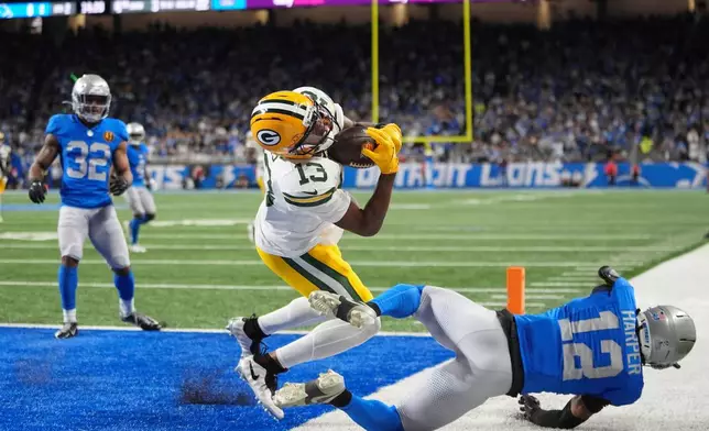 Green Bay Packers wide receiver Dontayvion Wicks (13) makes a catch for a touchdown over Detroit Lions safety Thomas Harper (12) during the first half an NFL football game in Detroit, Thursday, Nov. 27, 2025. (AP Photo/Ryan Sun)