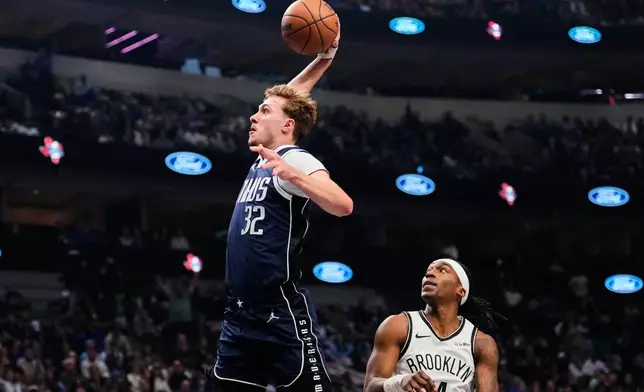 Dallas Mavericks forward Cooper Flagg (32) leaps to the basket to dunk after getting past Brooklyn Nets guard Terance Mann (14) in the first half of an NBA basketball game in Dallas, Friday, Dec. 12, 2025. (AP Photo/Tony Gutierrez)