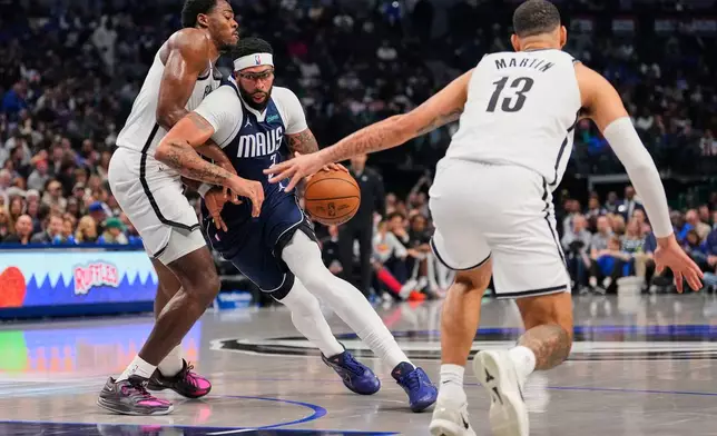 Dallas Mavericks forward Anthony Davis, center, works for a shot attempt against Brooklyn Nets' Day'Ron Sharpe, left, and Tyrese Martin (13) in the first half of an NBA basketball game in Dallas, Friday, Dec. 12, 2025. (AP Photo/Tony Gutierrez)