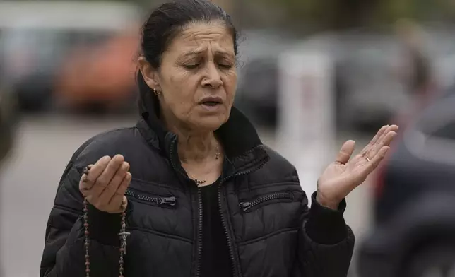 A woman prays while holding a rosary at the tomb of St. Charbel in the northern village of Annaya, Lebanon, Saturday, Nov. 15, 2025. (AP Photo/Hassan Ammar)