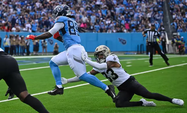 Tennessee Titans tight end Chig Okonkwo (85) carries on a touchdown reception against New Orleans Saints safety Jonas Sanker (33) in the first half of an NFL football game, Sunday, Dec. 28, 2025, in Nashville, Tenn. (AP Photo/John Amis)