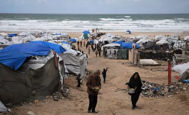 Palestinians receive donated food at a temporary camp for displaced people, on the beach near the port of Gaza City, Sunday, Dec. 28, 2025. (AP Photo/Jehad Alshrafi)