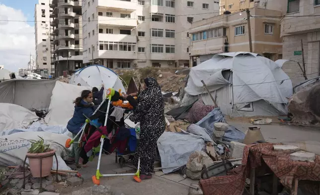 Members of the Al-Ajouri family stand by their tent that was destroyed by a strong wind and rain in Gaza City, Sunday, Dec. 28, 2025. (AP Photo/Jehad Alshrafi)
