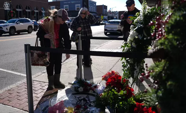 Nicole O'Healy, left, leaves flowers at the NC Auto Racing Walk of Fame for Greg Biffle, Friday, Dec. 19, 2025, in Mooresville, N.C. (AP Photo/Matt Kelley)