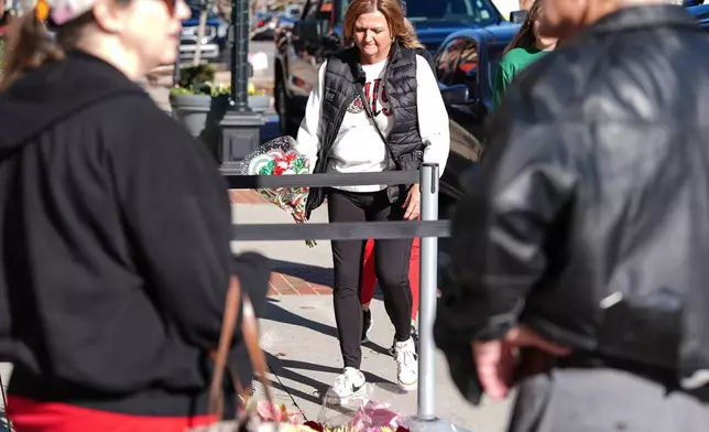 A supporter brings flowers to lay at the tribute at the NC Auto Racing Walk of Fame for Greg Biffle, Friday, Dec. 19, 2025, in Mooresville, N.C. (AP Photo/Matt Kelley)