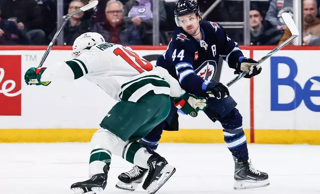 Winnipeg Jets' Josh Morrissey (44) defends against Minnesota Wild's Vincent Hinostroza (18) during second-period NHL hockey game action in Winnipeg, Manitoba, Saturday, Dec. 27, 2025. (John Woods/The Canadian Press via AP)