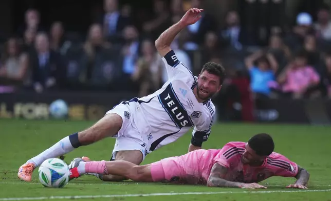 Vancouver Whitecaps' Thomas Muller (top) is taken down by Inter Miami's Rodrigo de Paul (right) during the first half of the MLS Cup final soccer match in Fort Lauderdale, Fla., on Saturday, Dec. 6, 2025. (Darryl Dyck/The Canadian Press via AP)