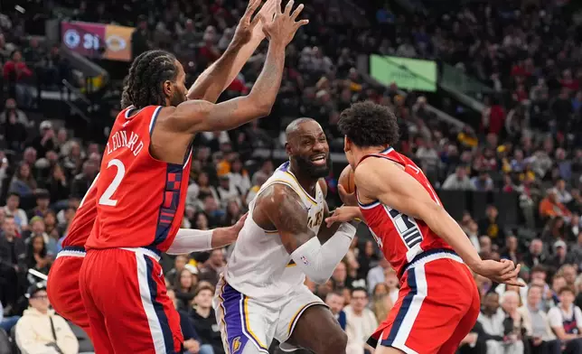 Los Angeles Lakers forward Lebron James, center, is defended by Los Angeles Clippers forward Kawhi Leonard, left, and guard Kobe Sanders during the first half of an NBA basketball game Saturday, Dec. 20, 2025, in Inglewood, Calif. (AP Photo/Jae C. Hong)