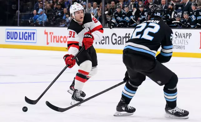 New Jersey Devils center Dawson Mercer (91) passes the puck past Utah Mammoth center Jack McBain (22) during the second period of an NHL hockey game, Friday, Dec. 19, 2025, in Salt Lake City. (AP Photo/Tyler Tate)