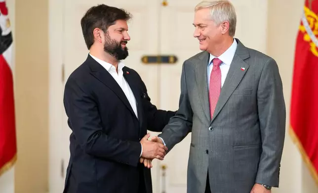 Chilean President Gabriel Boric, left, welcomes President-elect Jose Antonio Kast to La Moneda palace the day after Kast won the presidential election runoff in Santiago, Chile, Monday, Dec. 15, 2025. (AP Photo/Esteban Felix)