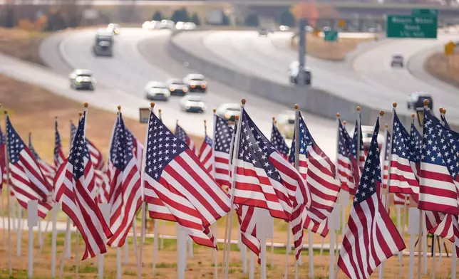 Flags are seen near a roadside memorial, Nov. 17, 2025, in Lowell, Ark. (AP Photo/Julio Cortez)