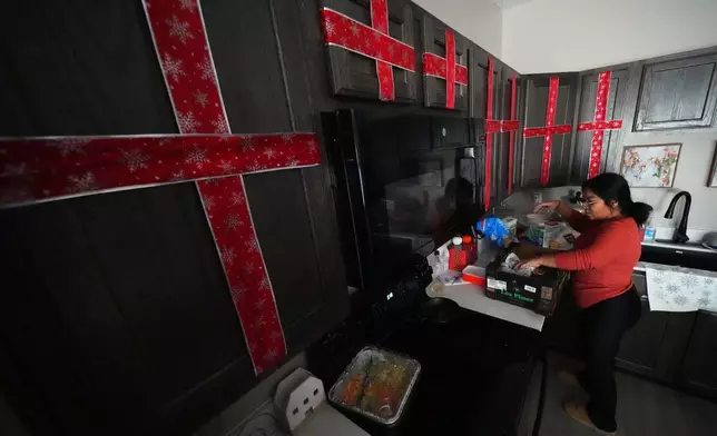 Cristina Osornio unpacks a box of groceries that was delivered to her home by a member of a community group, Nov. 18, 2025, in Rogers, Ark. (AP Photo/Julio Cortez)