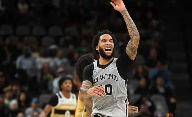 San Antonio Spurs forward Julian Champagnie, foreground, reacts as his team pulls away against the Washington Wizards during the second half of an NBA basketball game in San Antonio, Thursday, Dec. 18, 2025. (AP Photo/Billy Calzada)