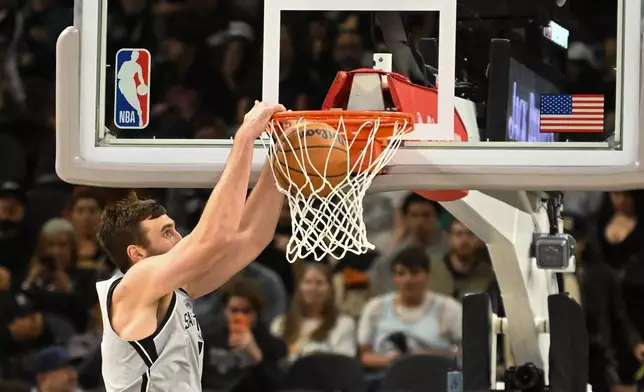 San Antonio Spurs center Luke Kornet dunks the ball against the Washington Wizards during the first half of an NBA basketball game in San Antonio, Thursday, Dec. 18, 2025. (AP Photo/Billy Calzada)