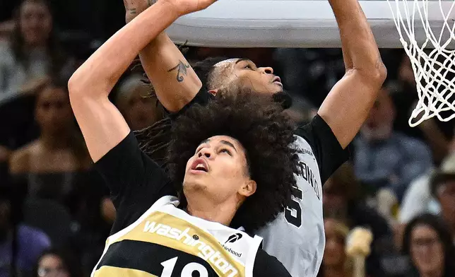 Washington Wizards forward Kyshawn George (18) and San Antonio Spurs guard Stephon Castle (5) battle for a rebound during the first half of an NBA basketball game in San Antonio, Thursday, Dec. 18, 2025. (AP Photo/Billy Calzada)