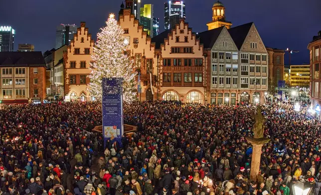 People gather at Roemerberg square to attend the city's bell ringing on Christmas Eve in Frankfurt, Germany, Wednesday, Dec. 24, 2025. (AP Photo/Michael Probst)
