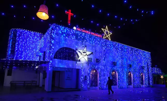 A man walks past an illuminated church on the eve of Christmas in Ahmedabad, India, Wednesday, Dec. 24, 2025. (AP Photo/Ajit Solanki)