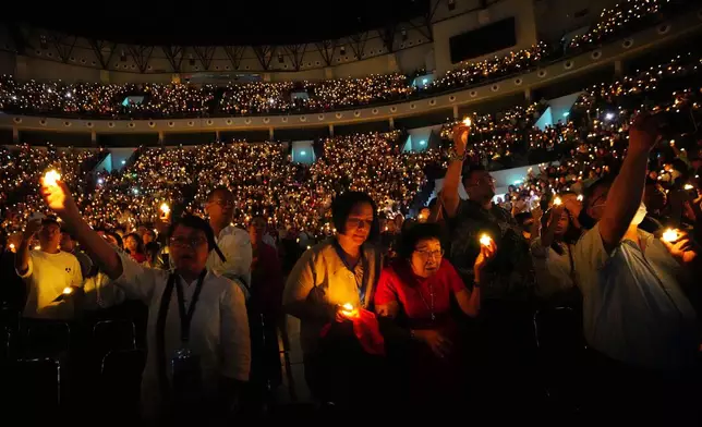 People hold electric candles as they sing during a Christmas Eve service at Indonesia Arena stadium in Jakarta, Indonesia, Wednesday, Dec. 24, 2025. (AP Photo/Tatan Syuflana)