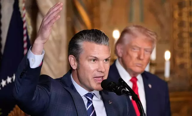 Defense Secretary Pete Hegseth speaks as President Donald Trump looks on, at Trump's Mar-a-Lago club, Monday, Dec. 22, 2025, in Palm Beach, Fla. (AP Photo/Alex Brandon)