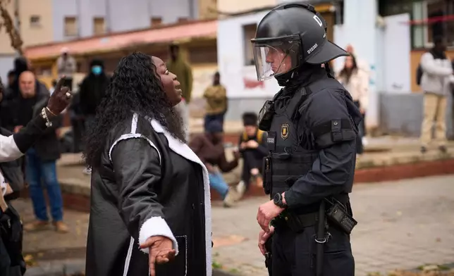 A migrant argues with a riot police officer as police begin carrying out eviction orders at an abandoned school building where hundreds of mostly undocumented migrants had been living, in Badalona, near Barcelona, Spain, Wednesday, Dec. 17, 2025. (AP Photo/Emilio Morenatti)