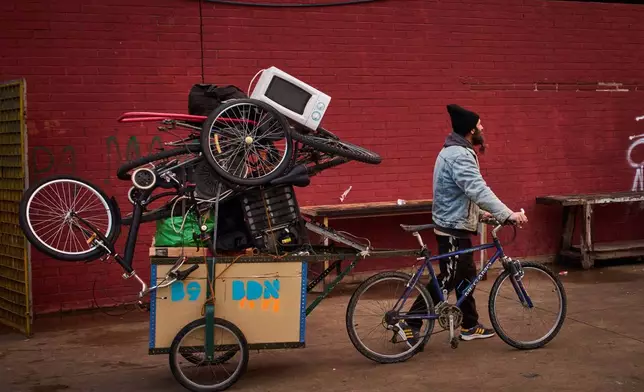 A migrant carries his belongings as police began carrying out eviction orders at an abandoned school building where hundreds of mostly undocumented migrants had been living, in Badalona, near Barcelona, Spain, Wednesday, Dec. 17, 2025. (AP Photo/Emilio Morenatti)