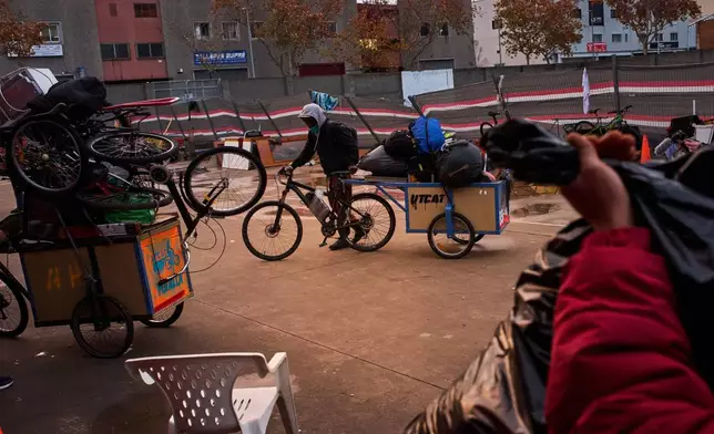 Migrants carry their belongings as they leave while police begin carrying out eviction orders at an abandoned school building where hundreds of mostly undocumented migrants had been living, in Badalona, near Barcelona, Spain, Wednesday, Dec. 17, 2025. (AP Photo/Emilio Morenatti)