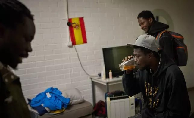 Migrants from Senegal gather to drink coffee at a makeshift bar shortly before police begin carrying out eviction orders at an abandoned school building where hundreds of mostly undocumented migrants had been living, in Badalona, near Barcelona, Spain, Wednesday, Dec. 17, 2025. (AP Photo/Emilio Morenatti)