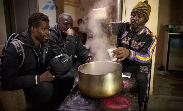 Migrants from Senegal gather to drink coffee at a makeshift bar as police began carrying out eviction orders at an abandoned school building where hundreds of mostly undocumented migrants had been living, in Badalona, near Barcelona, Spain, Wednesday, Dec. 17, 2025.(AP Photo/Emilio Morenatti)