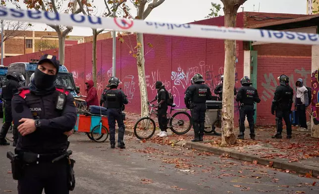 Migrants leave under police escort after being evicted from an abandoned school where they had been living in Badalona, near Barcelona, Spain, Wednesday, Dec. 17, 2025. (AP Photo/Emilio Morenatti)