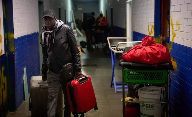 A migrant carries his belongings, as police began carrying out eviction orders at an abandoned school building where hundreds of mostly undocumented migrants had been living, in Badalona, near Barcelona, Spain, Wednesday, Dec. 17, 2025.(AP Photo/Emilio Morenatti)