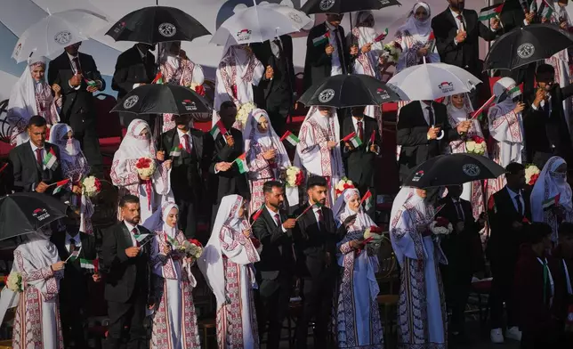 Palestinian couples participate in a mass wedding ceremony in Hamad City in Khan Younis, Gaza Strip, Tuesday, Dec. 2, 2025. (AP Photo/Abdel Kareem Hana)