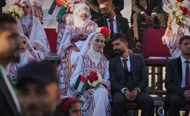 Palestinian couple Hikmat Lawwa and Eman Lawwa, center, join other newlyweds in a mass wedding ceremony at Hamad City in Khan Younis, southern Gaza Strip, Tuesday, Dec. 2, 2025. (AP Photo/Abdel Kareem Hana)