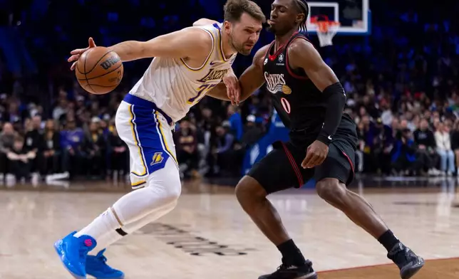 Los Angeles Lakers' Luka Doncic, left, makes his move against Philadelphia 76ers' Tyrese Maxey during the first half of an NBA basketball game, Sunday, Dec. 7, 2025, in Philadelphia. (AP Photo/Chris Szagola)