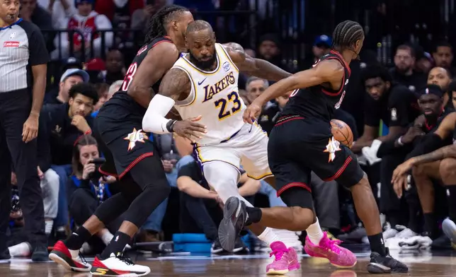 Los Angeles Lakers' LeBron James, center, gets the ball stolen by Philadelphia 76ers' Tyrese Maxey, right, as Jabari Walker, left, is defending during the second half of an NBA basketball game, Sunday, Dec. 7, 2025, in Philadelphia. (AP Photo/Chris Szagola)