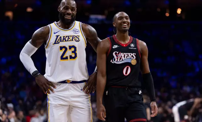 Los Angeles Lakers' LeBron James, left, talks with Philadelphia 76ers' Tyrese Maxey, right, during the first half of an NBA basketball game, Sunday, Dec. 7, 2025, in Philadelphia. (AP Photo/Chris Szagola)