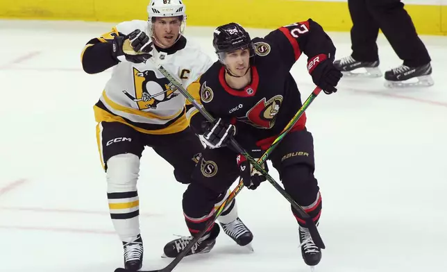 Pittsburgh Penguins' Sidney Crosby (87) battles with Ottawa Senators' Dylan Cozens (24) during the first period of an NHL hockey game in Ottawa, Ontario, Thursday, Dec. 18, 2025. (Patrick Doyle/The Canadian Press via AP)